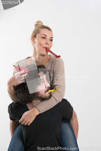 Image of couple in party hats blowing in whistle