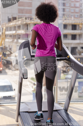 Image of afro american woman running on a treadmill