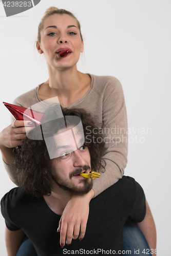 Image of couple in party hats blowing in whistle