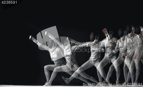 Image of Full-length portrait of woman wearing white fencing costume on black