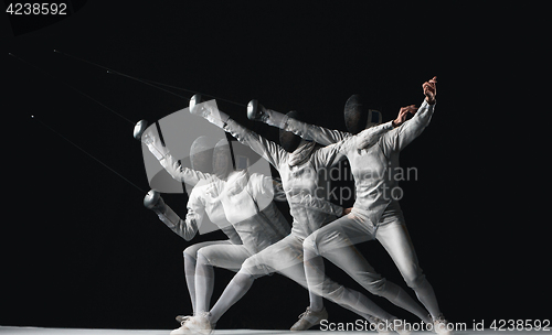 Image of Full-length portrait of woman wearing white fencing costume on black