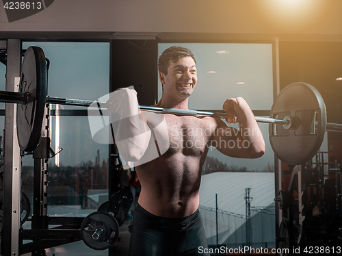 Image of Portrait of super fit muscular young man working out in gym with barbell