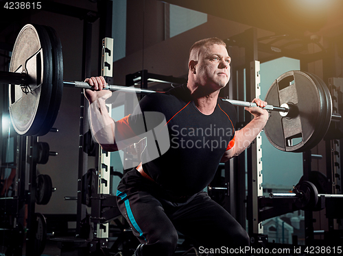 Image of Portrait of super fit muscular young man working out in gym with barbell