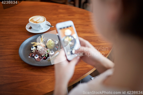 Image of woman with smartphone photographing food at cafe