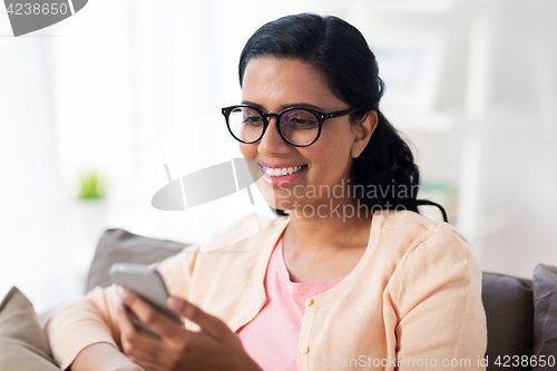 Image of happy woman texting message on smartphone at home