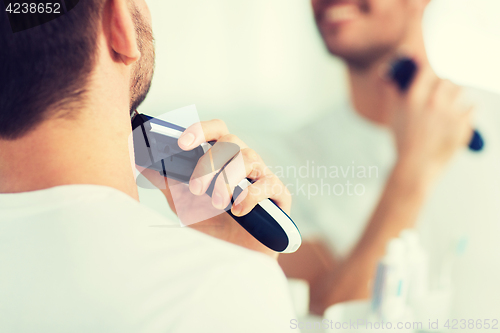 Image of close up of man shaving beard with trimmer