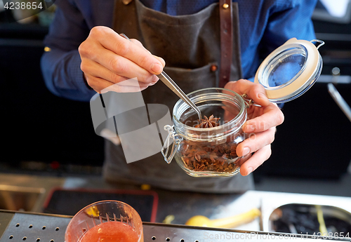 Image of bartender with anise preparing cocktail at bar