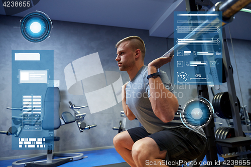 Image of young man flexing muscles with barbell in gym