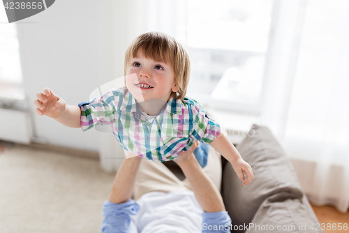 Image of father hands holding happy little boy at home