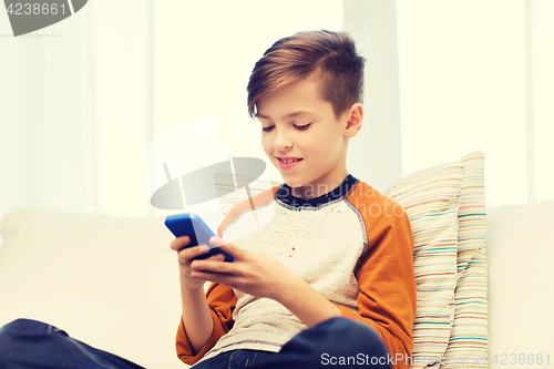 Image of boy with smartphone texting or playing at home