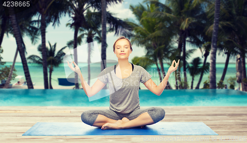 Image of woman making yoga meditation in lotus pose on mat