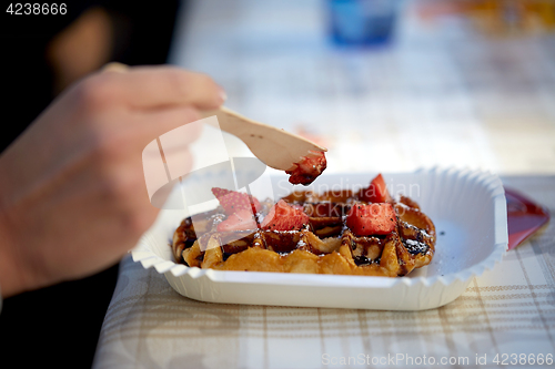 Image of close up of woman eating waffle with strawberry