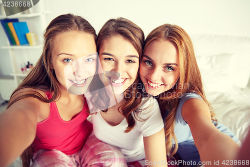 Image of happy friends or teen girls taking selfie at home