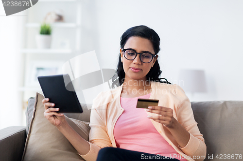 Image of happy woman with tablet pc and credit card at home