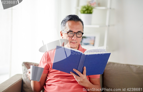 Image of man sitting on sofa and reading book at home