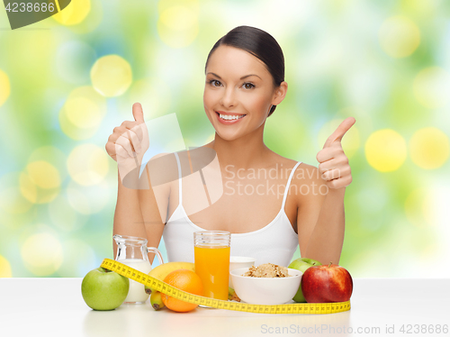 Image of woman with food and measure tape showing thumbs up