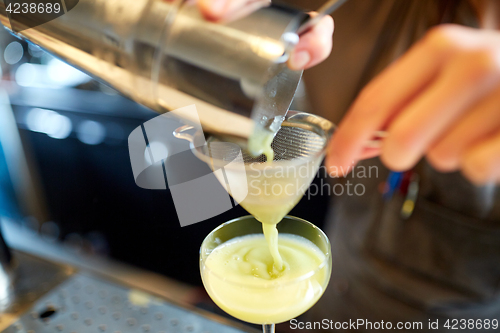 Image of bartender pouring cocktail into glass at bar