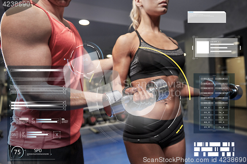 Image of young couple with dumbbell flexing muscles in gym