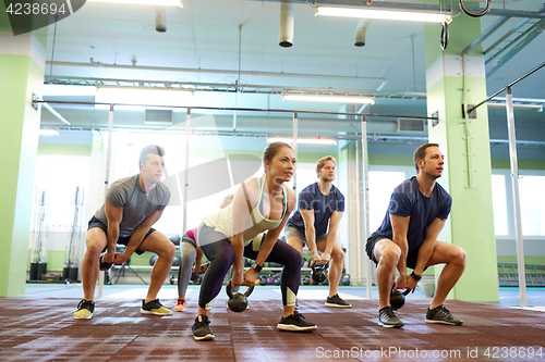 Image of group of people with kettlebells exercising in gym