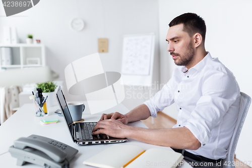 Image of businessman typing on laptop at office