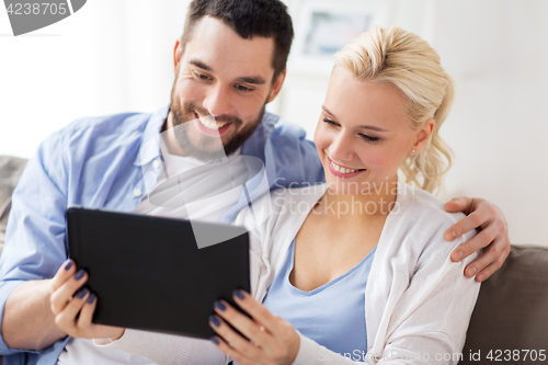 Image of smiling happy couple with tablet pc at home