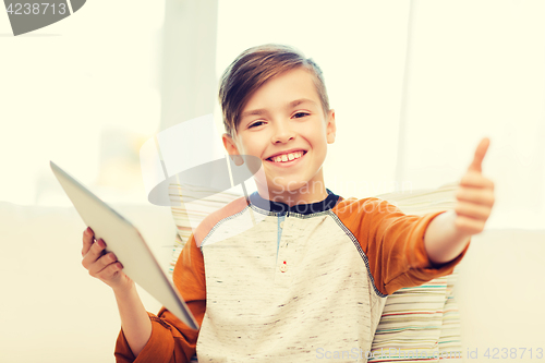Image of smiling boy with tablet showing thumbs up at home