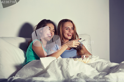 Image of happy friends with popcorn and watching tv at home