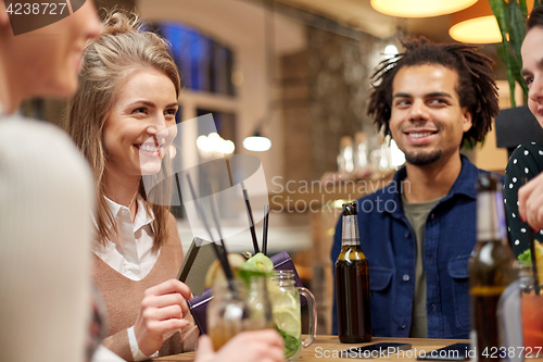 Image of friends with drinks, credit card and bill at bar