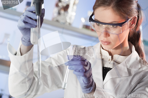 Image of Young scientist pipetting in life science laboratory.