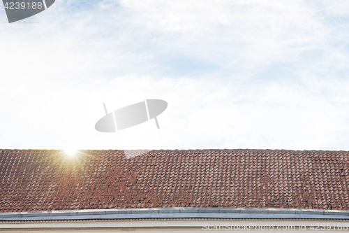 Image of cloudy blue sky and tiled roof top