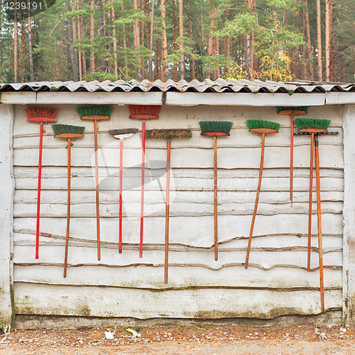 Image of Lot of brooms hanging on the wooden wall