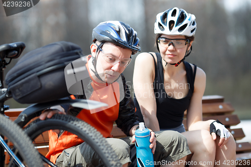 Image of Two bikers rest on bench