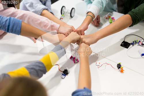 Image of happy children making fist bump at robotics school