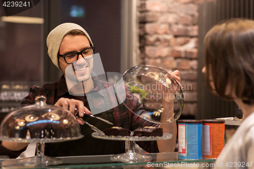 Image of man or barman with cakes serving customer at cafe