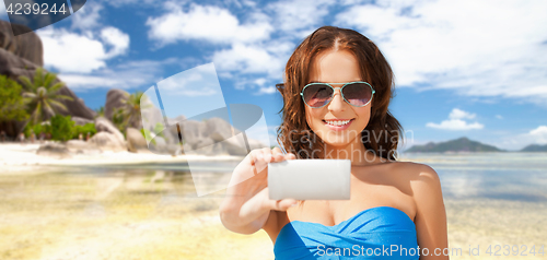 Image of woman in swimsuit taking selfie with smatphone