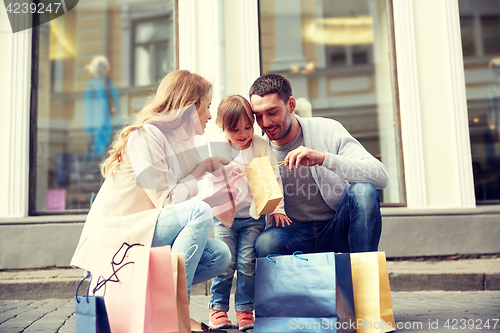 Image of happy family with child and shopping bags in city