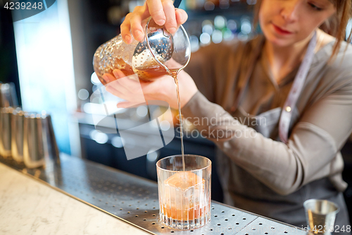 Image of bartender with glass and jug preparing cocktail