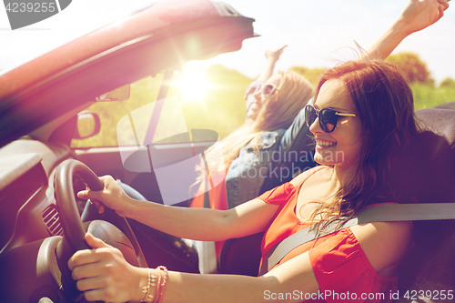 Image of smiling young women driving in cabriolet car