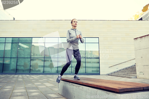 Image of woman making step exercise on city street bench