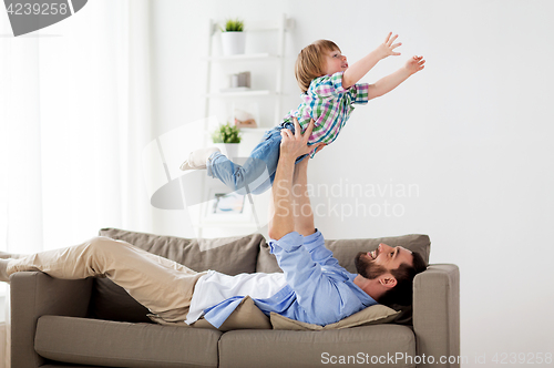 Image of happy young father playing with little son at home