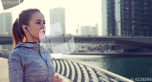 Image of happy woman with earphones running over dubai city