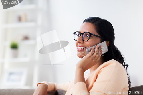 Image of happy indian woman calling on smartphone at home