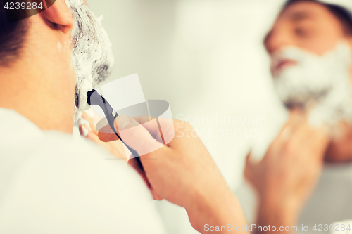 Image of close up of man shaving beard with razor blade