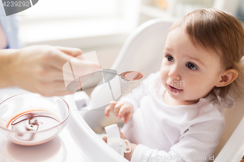 Image of mother feeding baby with puree at home