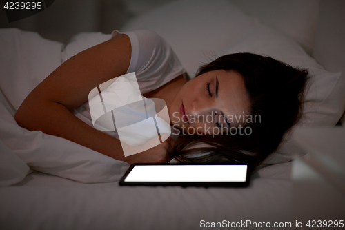 Image of woman with tablet pc sleeping in bed at night