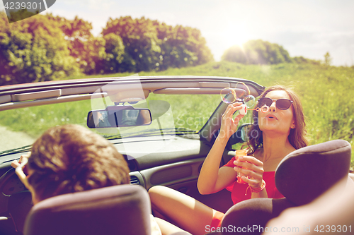 Image of friends driving in car and blowing bubbles