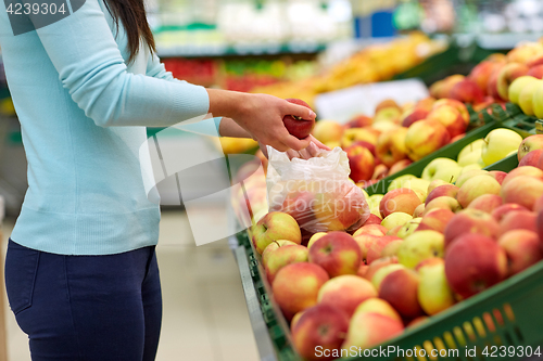 Image of woman with bag buying apples at grocery store