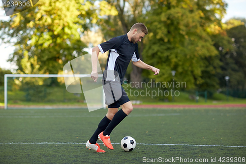 Image of soccer player playing with ball on football field