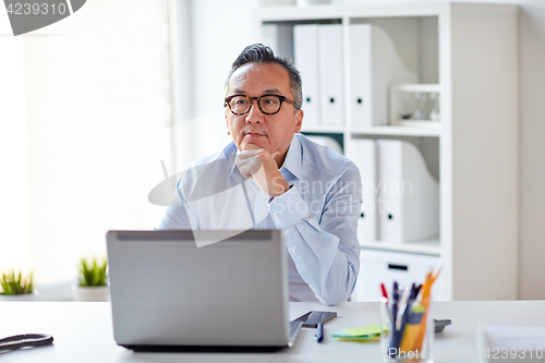 Image of businessman in eyeglasses with laptop office