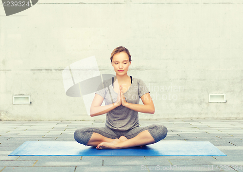 Image of woman making yoga meditation in lotus pose on mat